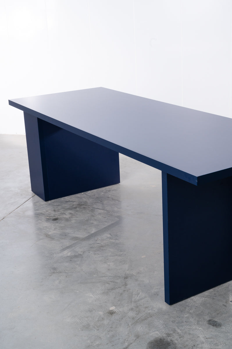 Detail of large rectangular wooden dining table in deep dark blue designed by Bobbie Bahama