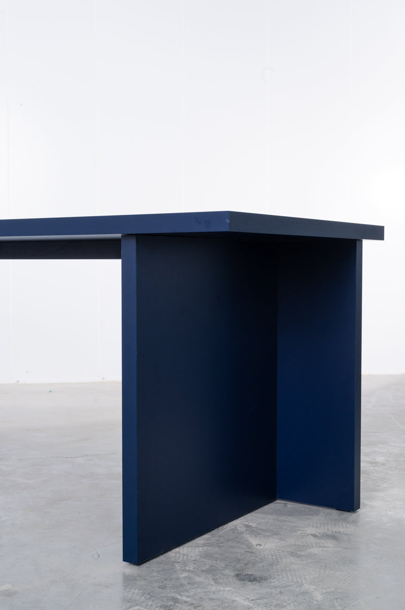 Detail of large rectangular wooden dining table in deep dark blue designed by Bobbie Bahama