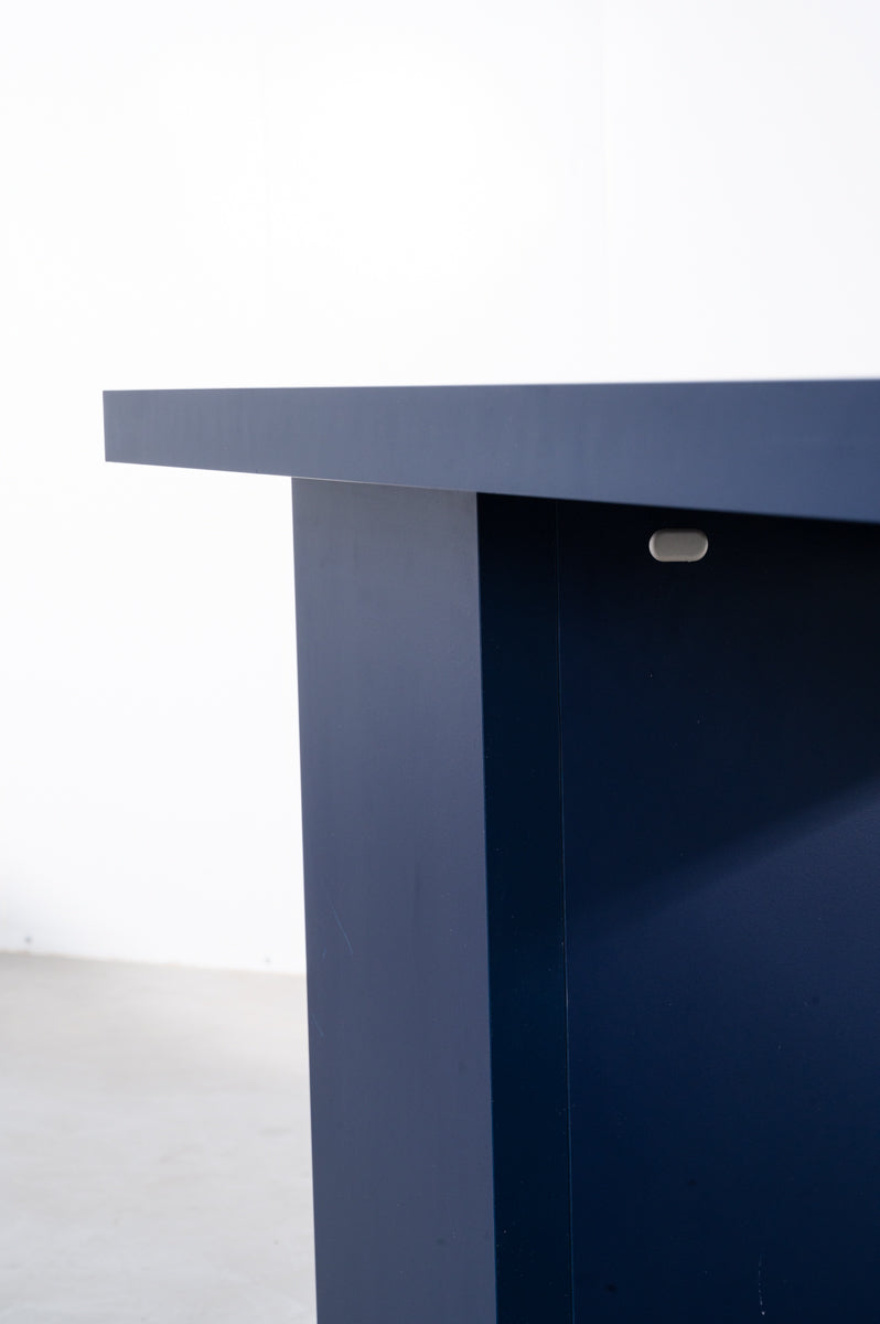Detail of large rectangular wooden dining table in deep dark blue designed by Bobbie Bahama