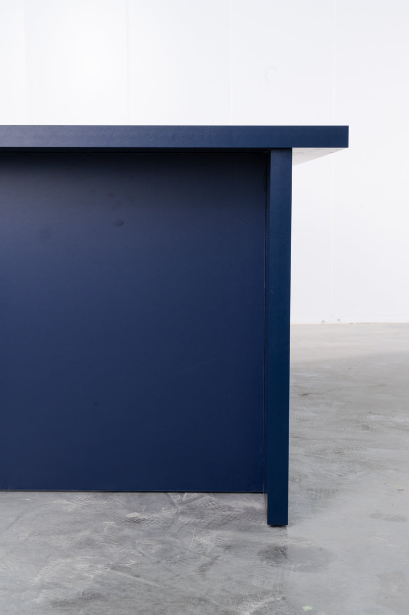 Detail of large rectangular wooden dining table in deep dark blue designed by Bobbie Bahama