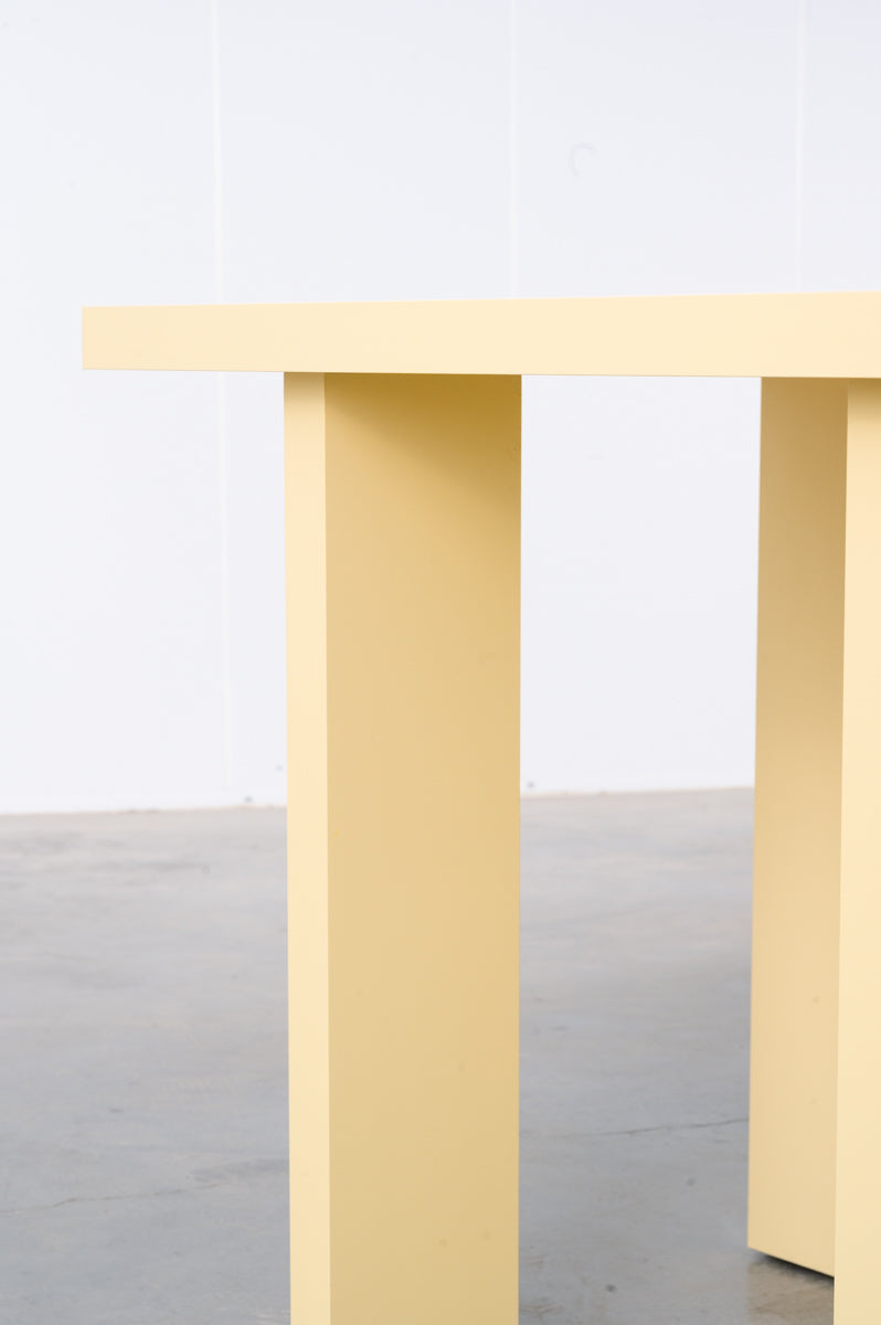Detail of rectangular wooden dining table in butter yellow designed by Bobbie Bahama